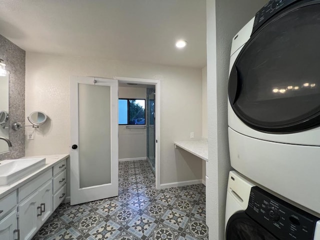 clothes washing area featuring sink and stacked washing maching and dryer