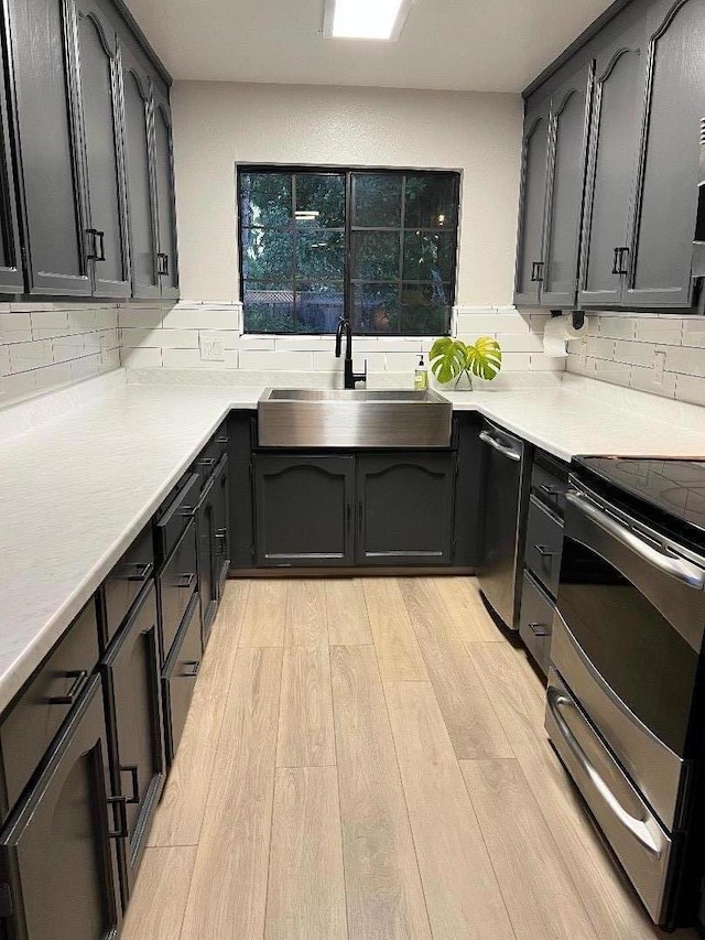 kitchen featuring sink, light hardwood / wood-style floors, tasteful backsplash, and appliances with stainless steel finishes