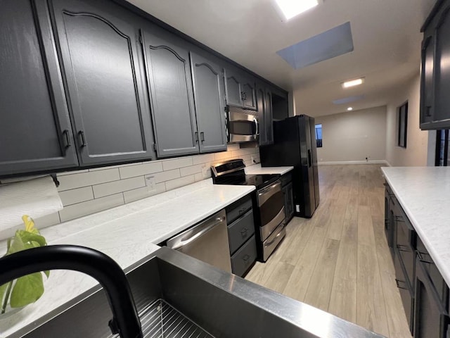 kitchen with light hardwood / wood-style floors, appliances with stainless steel finishes, and tasteful backsplash