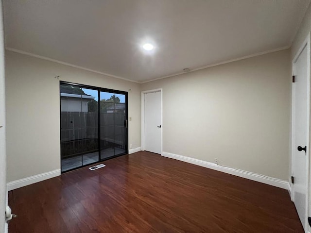 spare room with ornamental molding and dark hardwood / wood-style flooring