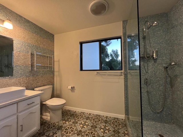 bathroom featuring tile patterned floors, tile walls, a tile shower, toilet, and vanity