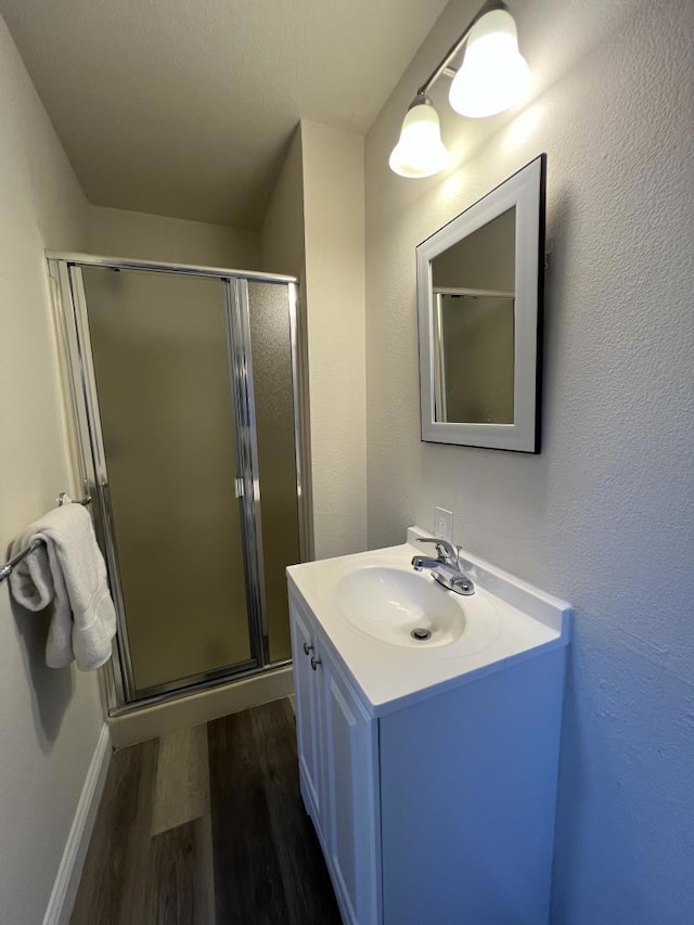 bathroom featuring hardwood / wood-style floors, a shower with door, and vanity