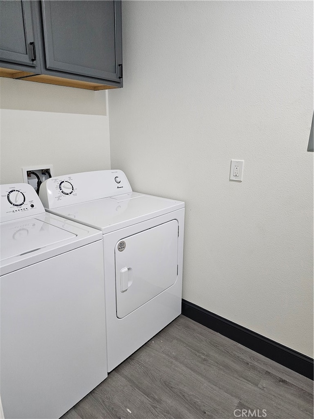 laundry room featuring independent washer and dryer, light hardwood / wood-style floors, and cabinets