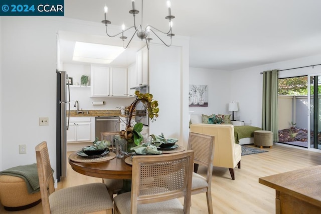 dining space featuring light wood-type flooring, sink, and a chandelier