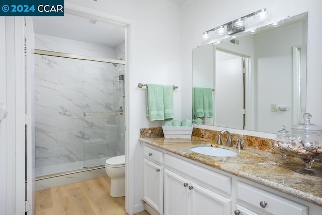 bathroom featuring hardwood / wood-style flooring, an enclosed shower, vanity, and toilet