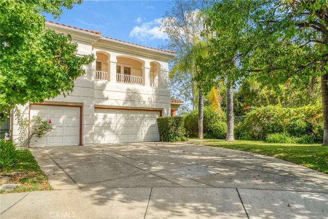 mediterranean / spanish-style house featuring a garage, concrete driveway, a front yard, and a balcony