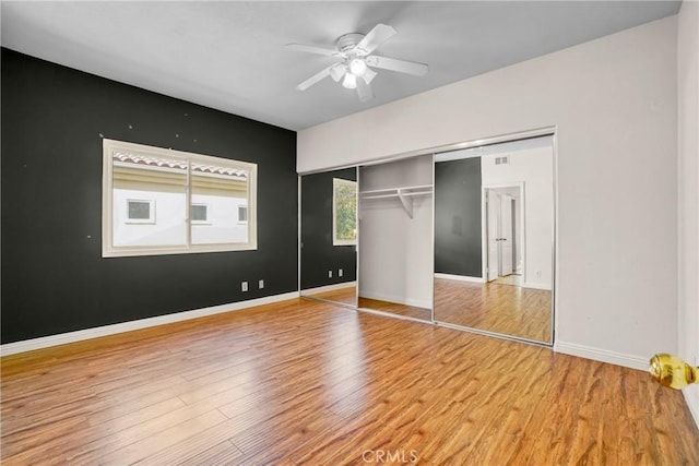 unfurnished bedroom featuring ceiling fan, a closet, baseboards, and wood finished floors