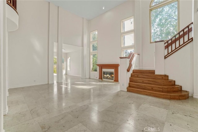 entryway with a glass covered fireplace, baseboards, stairway, and a high ceiling