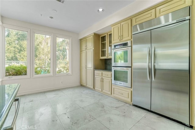 kitchen with cream cabinets, recessed lighting, marble finish floor, appliances with stainless steel finishes, and glass insert cabinets