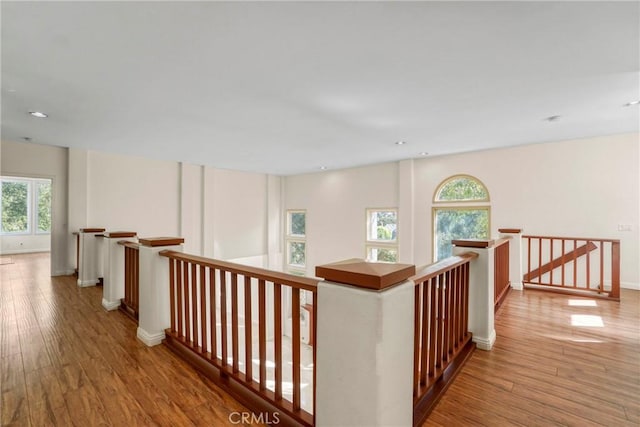 hallway featuring wood finished floors, an upstairs landing, and baseboards