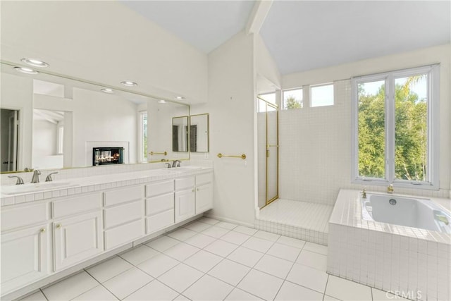 full bath featuring double vanity, vaulted ceiling, a sink, and a bath