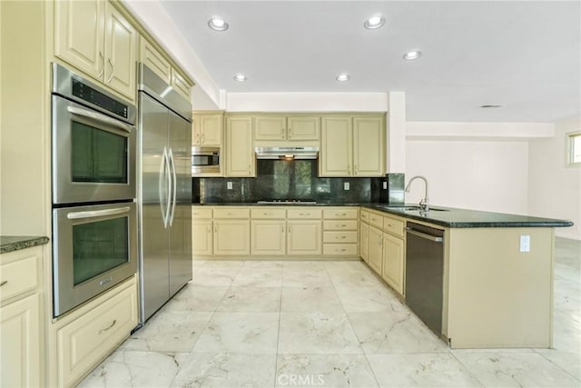 kitchen featuring built in appliances, under cabinet range hood, a sink, marble finish floor, and dark countertops