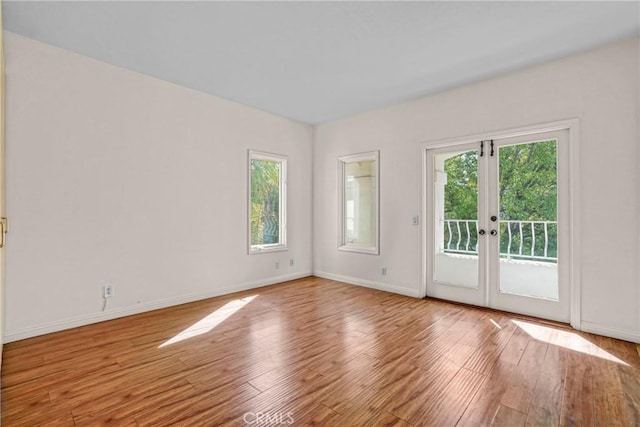 spare room with a healthy amount of sunlight, wood finished floors, and french doors