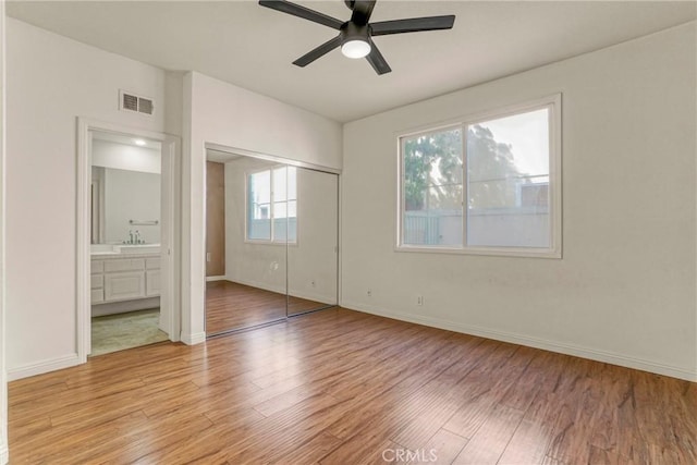 unfurnished bedroom featuring light wood-style floors, a closet, visible vents, and a sink