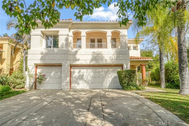 mediterranean / spanish-style home featuring stucco siding, concrete driveway, a balcony, a garage, and a tiled roof