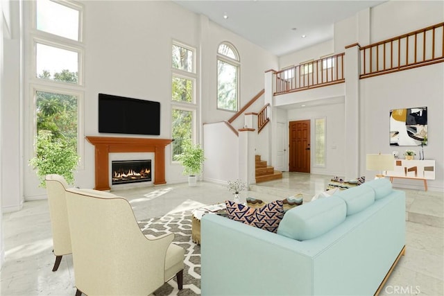 living room with stairway, recessed lighting, a warm lit fireplace, and a towering ceiling