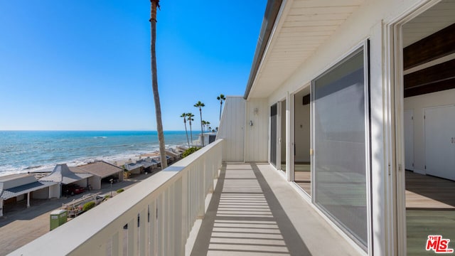 balcony featuring a view of the beach and a water view