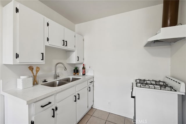 kitchen featuring white gas range, exhaust hood, sink, light tile patterned floors, and white cabinets