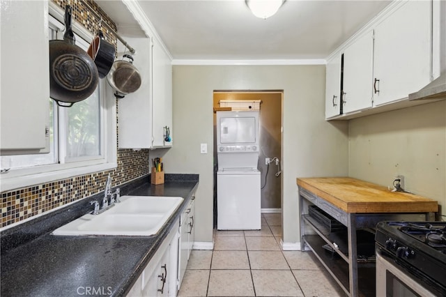 kitchen with stacked washer / dryer, sink, backsplash, and white cabinets