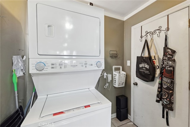 washroom with stacked washer / dryer, crown molding, and light tile patterned flooring