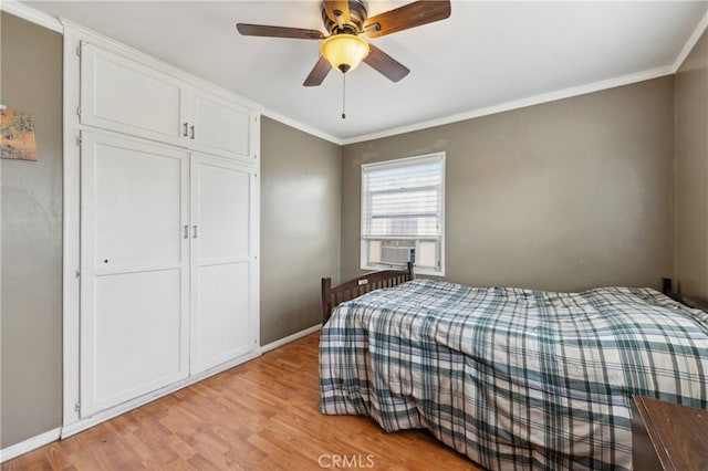 bedroom featuring a closet, ceiling fan, crown molding, and light wood-type flooring