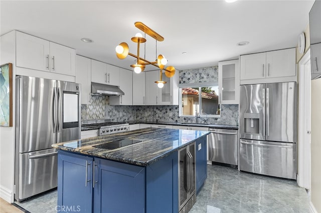 kitchen with dark stone countertops, appliances with stainless steel finishes, white cabinetry, and a kitchen island