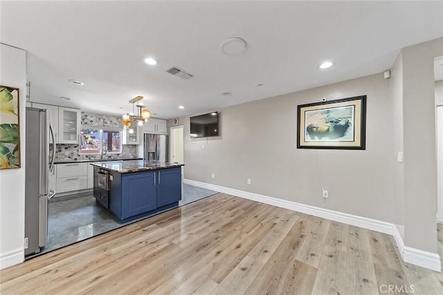 kitchen with stainless steel fridge, white cabinets, a kitchen island, light wood-type flooring, and stainless steel refrigerator