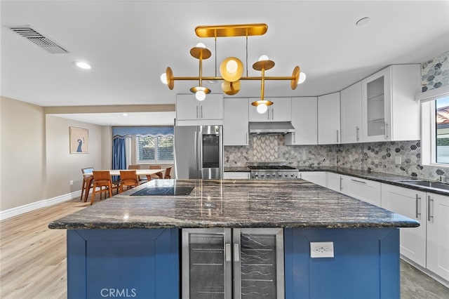 kitchen featuring a healthy amount of sunlight, stainless steel refrigerator, and white cabinets