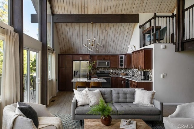 living room with a notable chandelier, beam ceiling, wooden ceiling, and sink