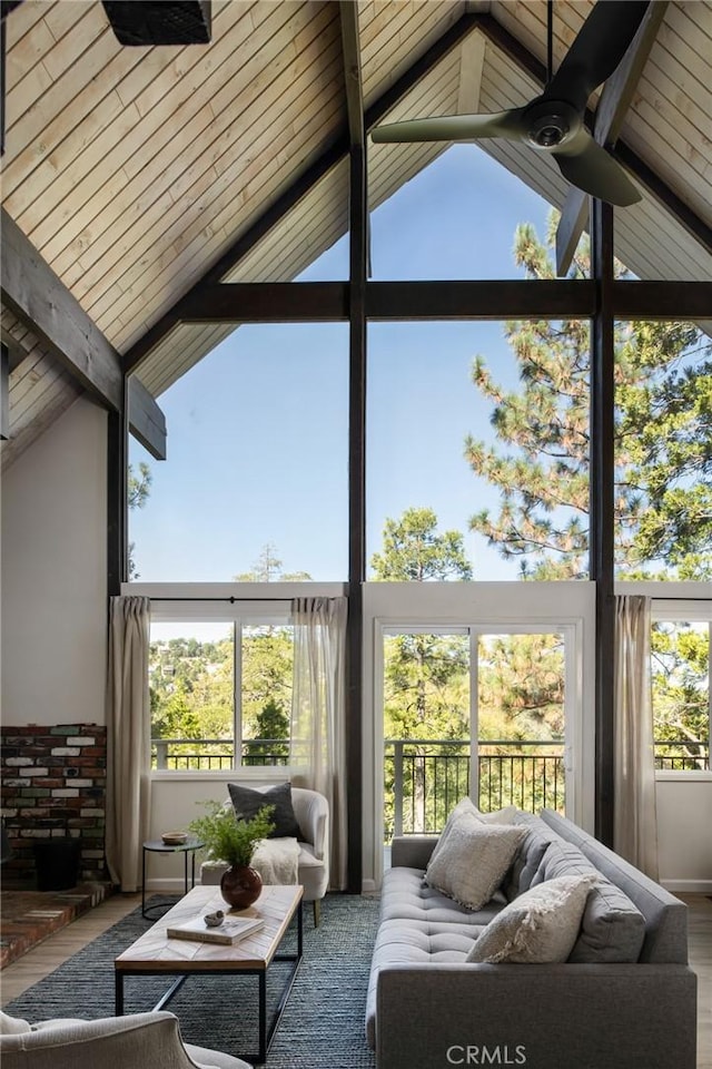 sunroom with vaulted ceiling with beams, ceiling fan, and wood ceiling