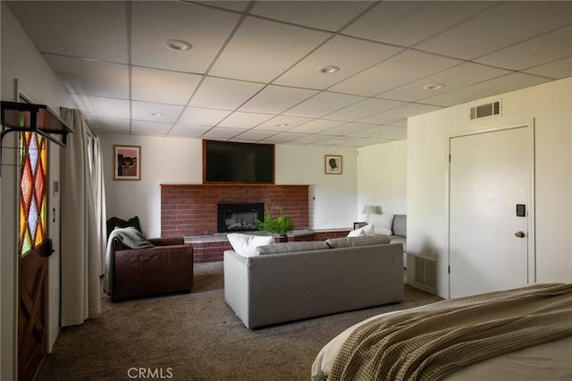 bedroom featuring dark colored carpet, a paneled ceiling, and a fireplace