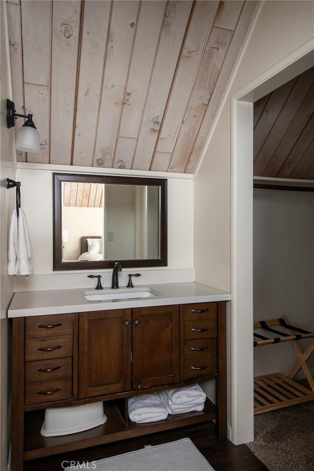 bathroom with wooden walls, vanity, and vaulted ceiling