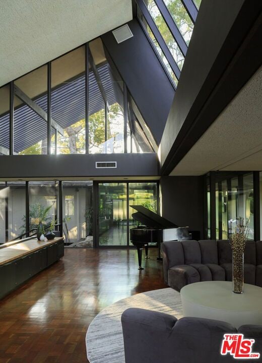 living room featuring high vaulted ceiling, a textured ceiling, and parquet flooring