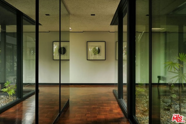 hallway with dark wood-type flooring, a textured ceiling, and a wall of windows