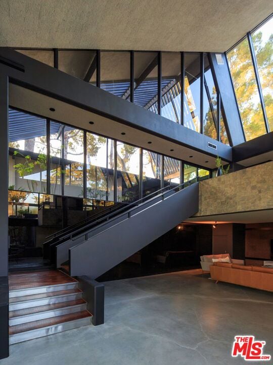 staircase with concrete flooring, a textured ceiling, high vaulted ceiling, and a wealth of natural light