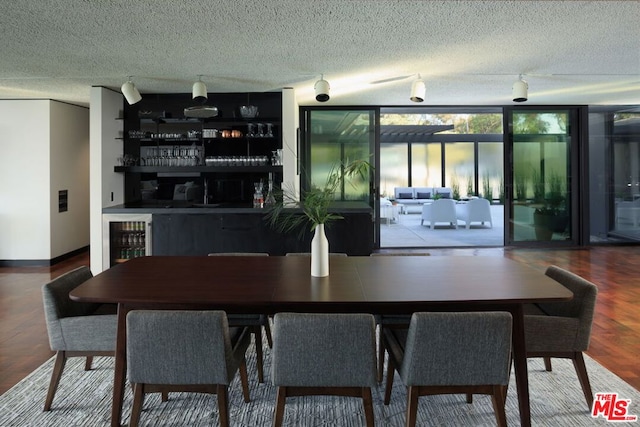 dining space featuring wine cooler, hardwood / wood-style floors, a textured ceiling, and a wall of windows