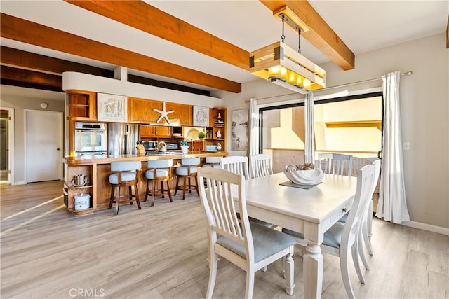 dining area featuring light hardwood / wood-style floors and beam ceiling