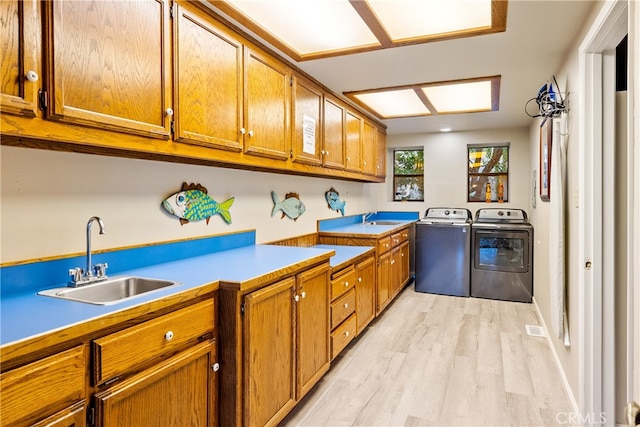 kitchen featuring light hardwood / wood-style floors, washing machine and dryer, and sink