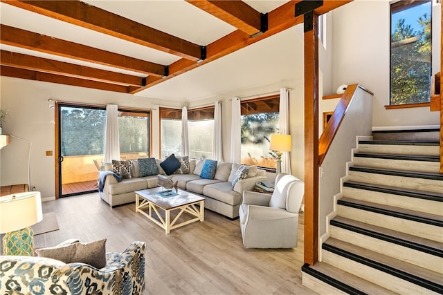 living room featuring beam ceiling, light hardwood / wood-style flooring, and a healthy amount of sunlight