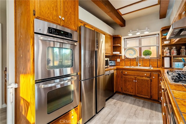 kitchen with sink, stainless steel appliances, beam ceiling, extractor fan, and light hardwood / wood-style flooring