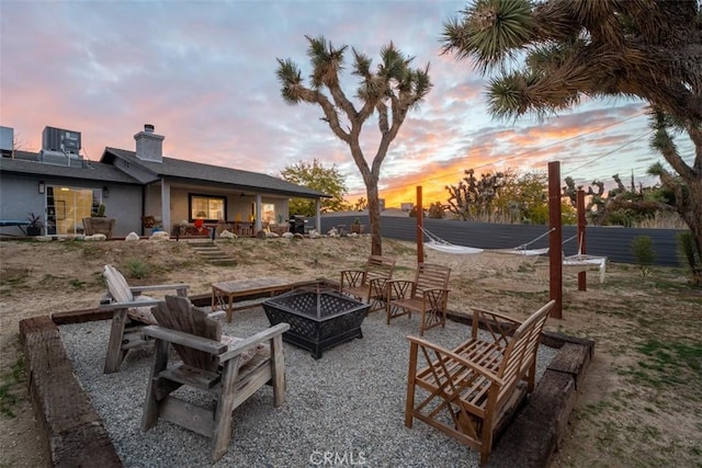 patio terrace at dusk with cooling unit and a fire pit