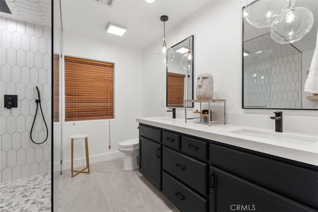 bathroom featuring tile patterned flooring, toilet, vanity, and tiled shower