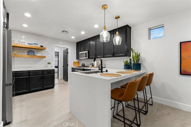 kitchen with sink, stainless steel appliances, tasteful backsplash, kitchen peninsula, and a breakfast bar area