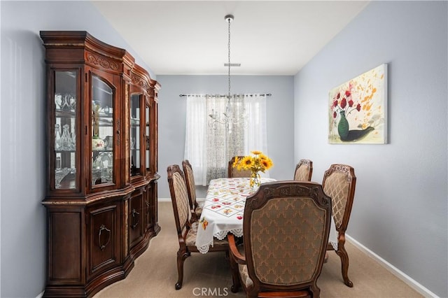 dining space featuring light colored carpet and an inviting chandelier