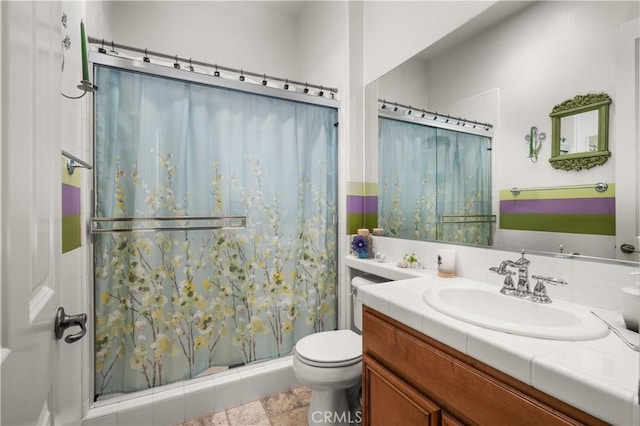 bathroom with tile patterned floors, vanity, toilet, and a shower