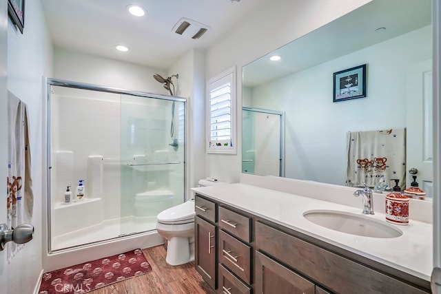 bathroom with vanity, toilet, hardwood / wood-style flooring, and a shower with door