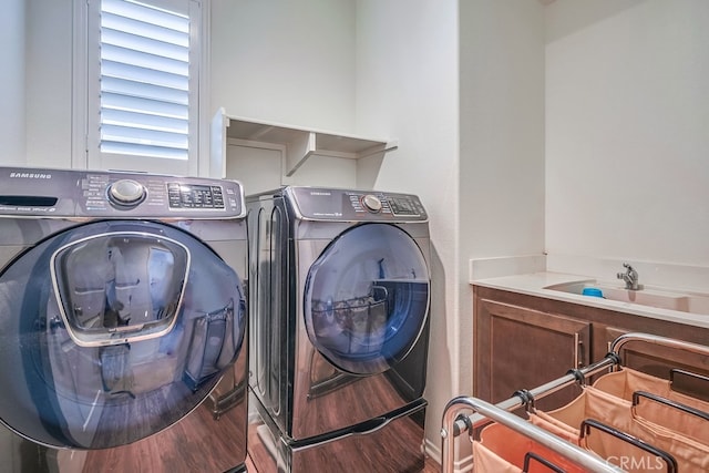 laundry area with cabinets, hardwood / wood-style flooring, sink, and washing machine and clothes dryer