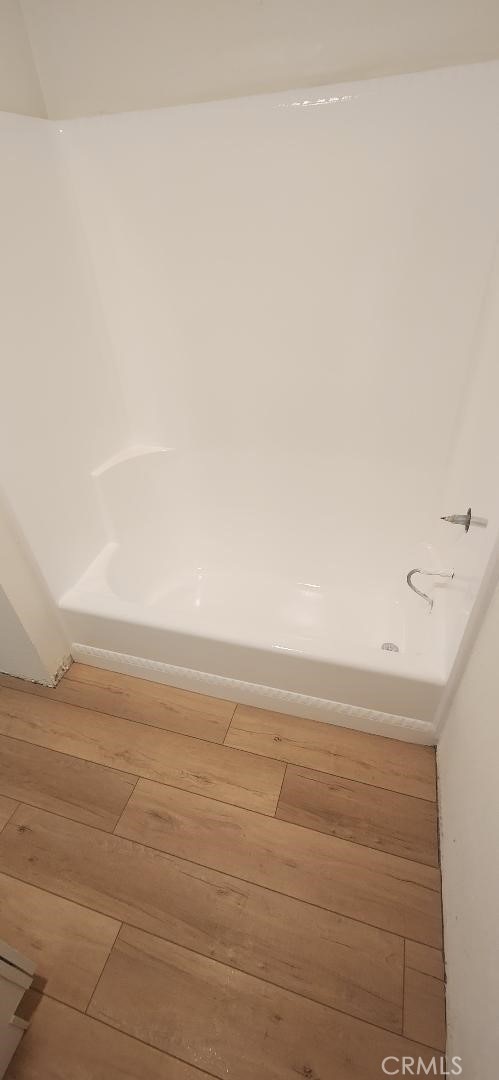 bathroom with a bath and wood finished floors