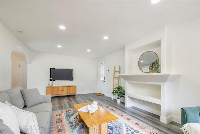 living area with baseboards, arched walkways, wood finished floors, and recessed lighting