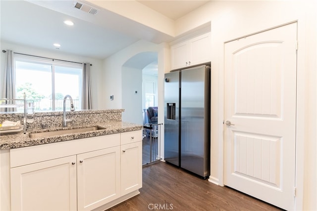 kitchen with dark hardwood / wood-style floors, sink, light stone countertops, stainless steel fridge, and white cabinetry